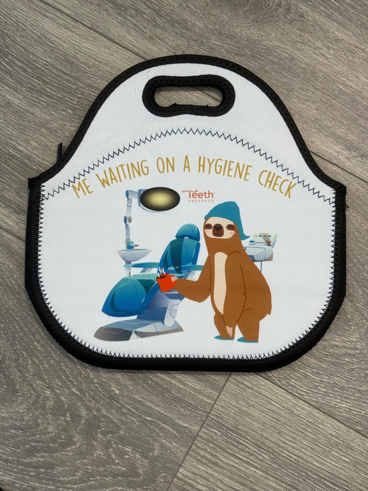 Teeth Obsessed insulated dental lunch bag with tooth design, featuring a tote style with handles and tooth-themed print.