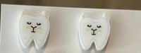 Dental earrings featuring a playful llama, koala, and cow tooth design from Teeth Obsessed, displayed on a neutral background.