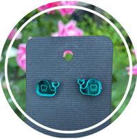 Whale-shaped dental earrings by Teeth Obsessed featuring silver-tone whale design on a white background.