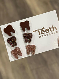 Rose gold dental earrings with tooth design from Teeth Obsessed, featuring a solid brown finish and unique dental jewelry style.