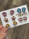 Teeth Obsessed Wonderland Dental Earrings featuring playful cat-shaped dental designs on silver hoops.