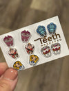 Teeth Obsessed Wonderland Dental Earrings featuring whimsical cat-shaped dental jewelry with colorful enamel accents.