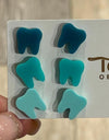 Dark turquoise dental earrings by Teeth Obsessed featuring tooth-shaped design and silver hooks.