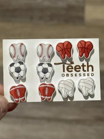 Teeth Obsessed sports ball tooth earring resembling a football, made as a unique dental jewelry accessory.