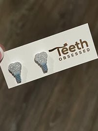 Glitter dental implant teeth earrings by Teeth Obsessed, featuring realistic tooth design and sparkling accents for a unique look.