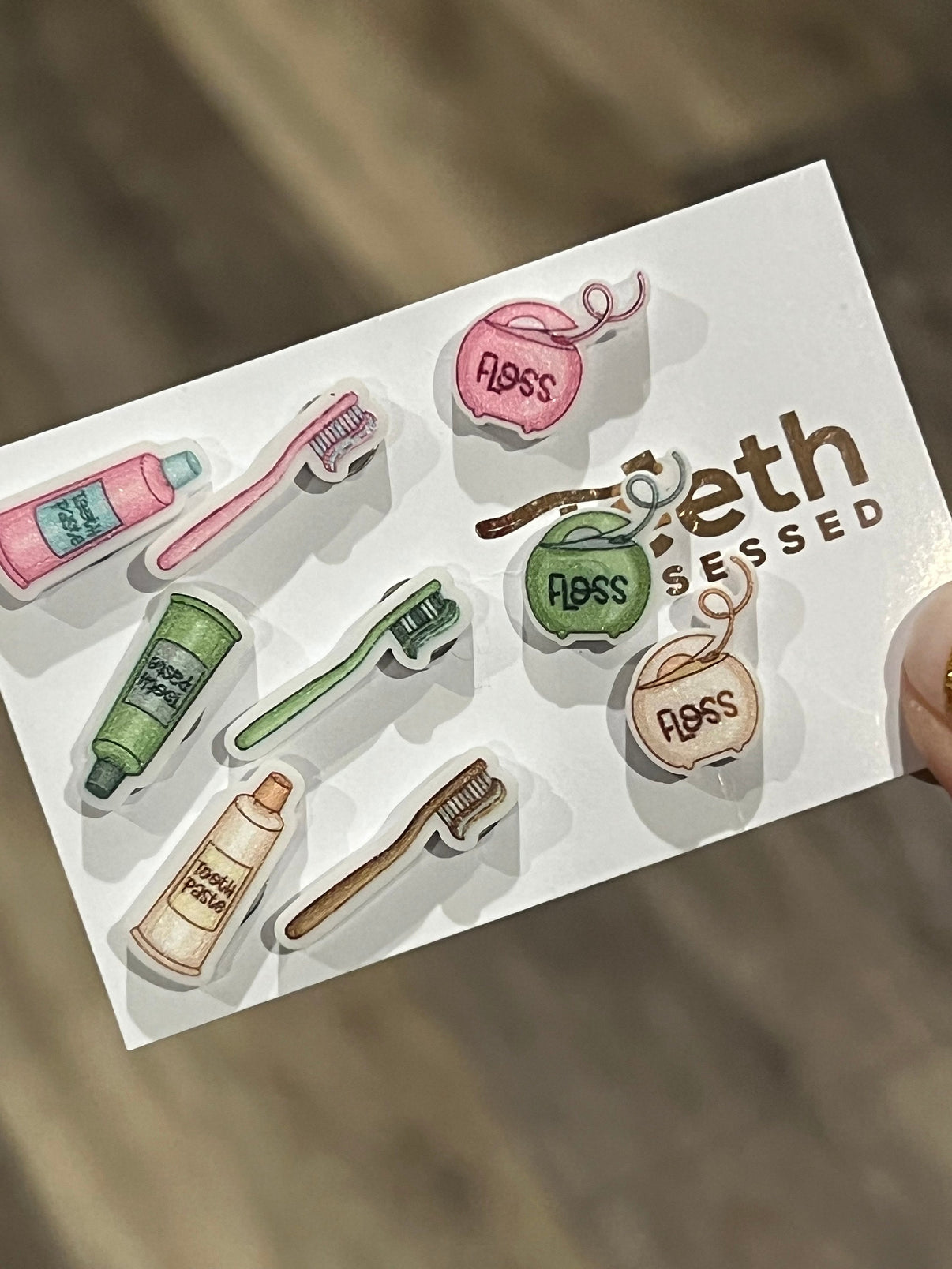 Pink dental earrings featuring miniature toothpaste, toothbrush, and floss designs from Teeth Obsessed, perfect for dental enthusiasts.
