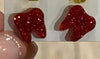Red and gold dental earrings by Teeth Obsessed, featuring playful tooth-shaped jewelry with vibrant red and gold accents.