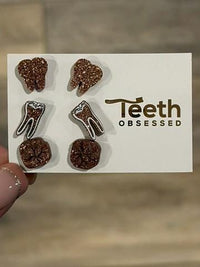 Tiny rose gold dental earrings by Teeth Obsessed featuring tooth-shaped designs for a stylish dental accessory.
