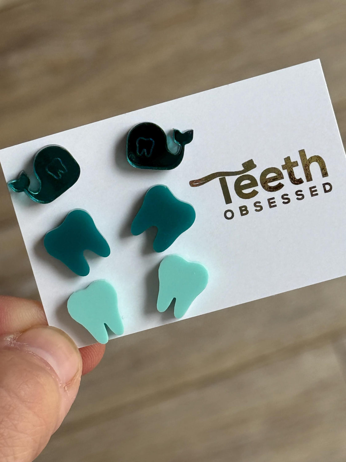 Teeth Obsessed teal whale dental earrings in dark and light teal, featuring whale-shaped design with tooth details.