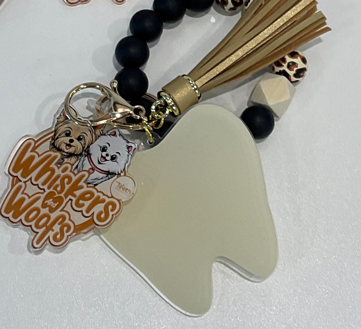 Cream dental keychains featuring Whiskers and Woofs characters from Teeth Obsessed, with detailed cat-themed designs.