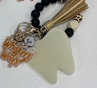 Cream dental keychains featuring Whiskers and Woofs characters from Teeth Obsessed, with detailed cat-themed designs.