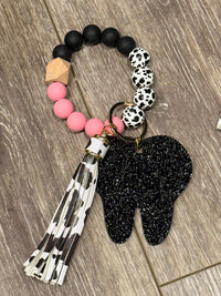 Pink cow-shaped dental keychain made of handmade acrylic, featuring a tooth design by Teeth Obsessed.