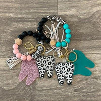 Pink and teal leopard print tooth keychains from Teeth Obsessed, featuring fun dental-themed accessories with a bold pattern.