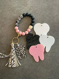 White leopard print dental keychain by Teeth Obsessed featuring a tooth-shaped design and keyring attachment.