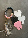 Leopard Tooth Dental Keychain by Teeth Obsessed featuring a white leopard-print design and a tooth-shaped charm.