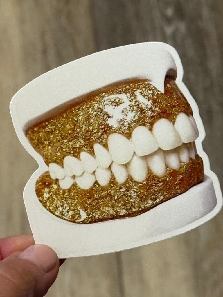 Gold glitter typodont dental sticker from Teeth Obsessed, featuring a shiny, decorative design for dental-themed crafts or displays.