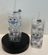Orthodontic drinking glass with smiling braces design in blue, silver, and rose by Teeth Obsessed, perfect for dental-themed drinkware.