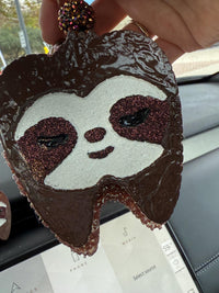 Teeth Obsessed sloth tooth car freshener vent clip in brown with vanilla scent, designed for car vents and freshening interiors.