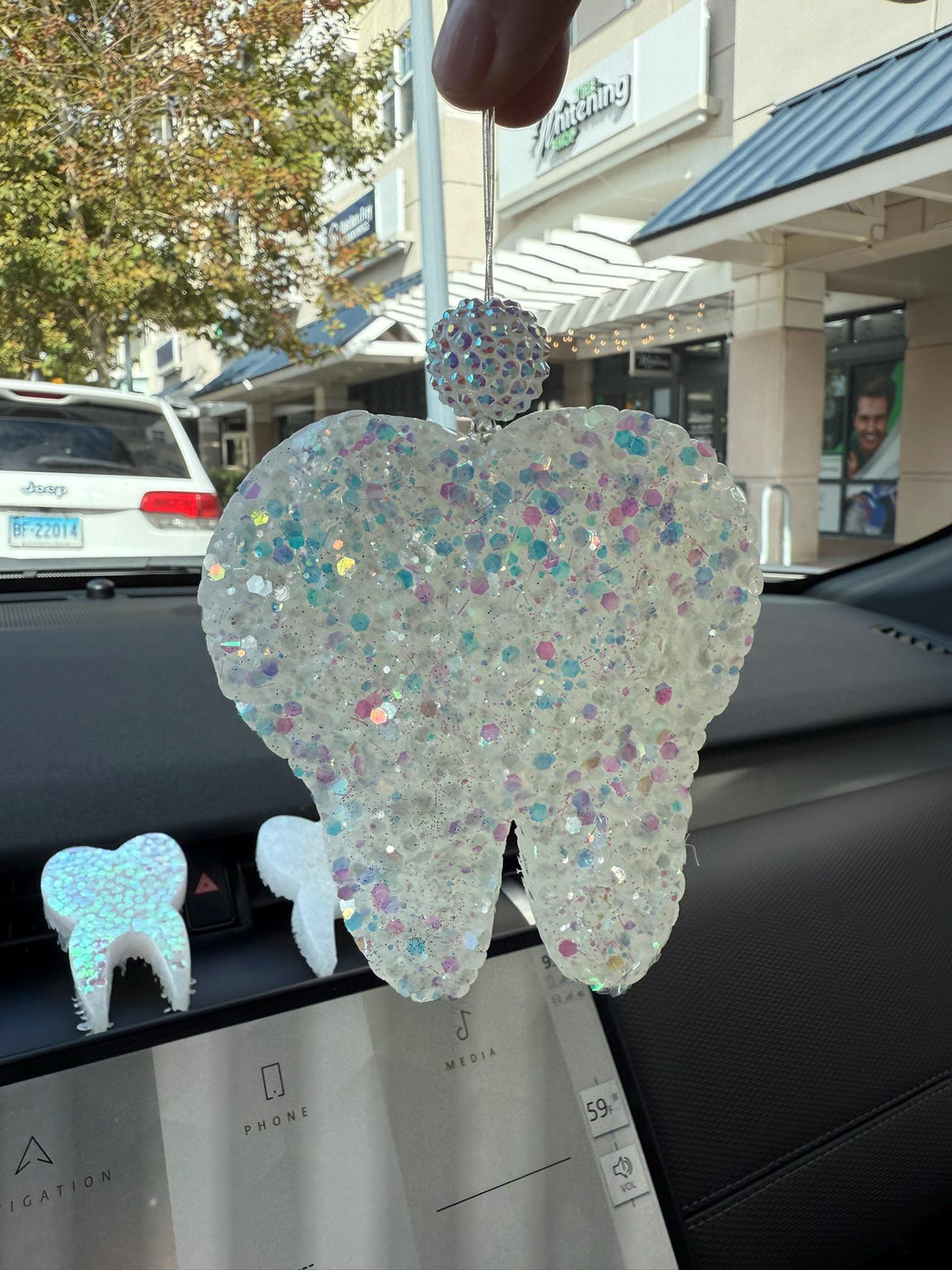 White glitter teeth-shaped car freshener from Teeth Obsessed, designed for vents and tart scent, adds a fun touch to your vehicle interior.
