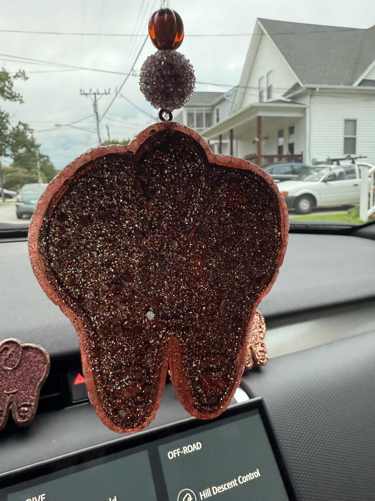 Dog Tooth Car Freshie and Vent Tart by Teeth Obsessed in brown, white, and tan, hanging from car vent, with vanilla scent.
