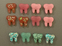 Pink acrylic tooth magnets and notepads from Teeth Obsessed, dental office decor featuring playful tooth-themed designs.