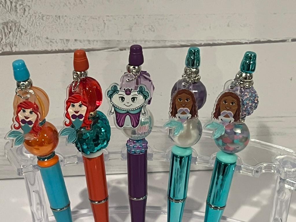 Blue Mermaid Tooth Pens from Teeth Obsessed displayed with matching holder, featuring a mermaid design and tooth-shaped tips.