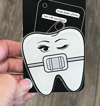 Teeth Obsessed Brace Tooth Phone Grip showing a quirky dental-themed design for easy phone handling and stand functionality.