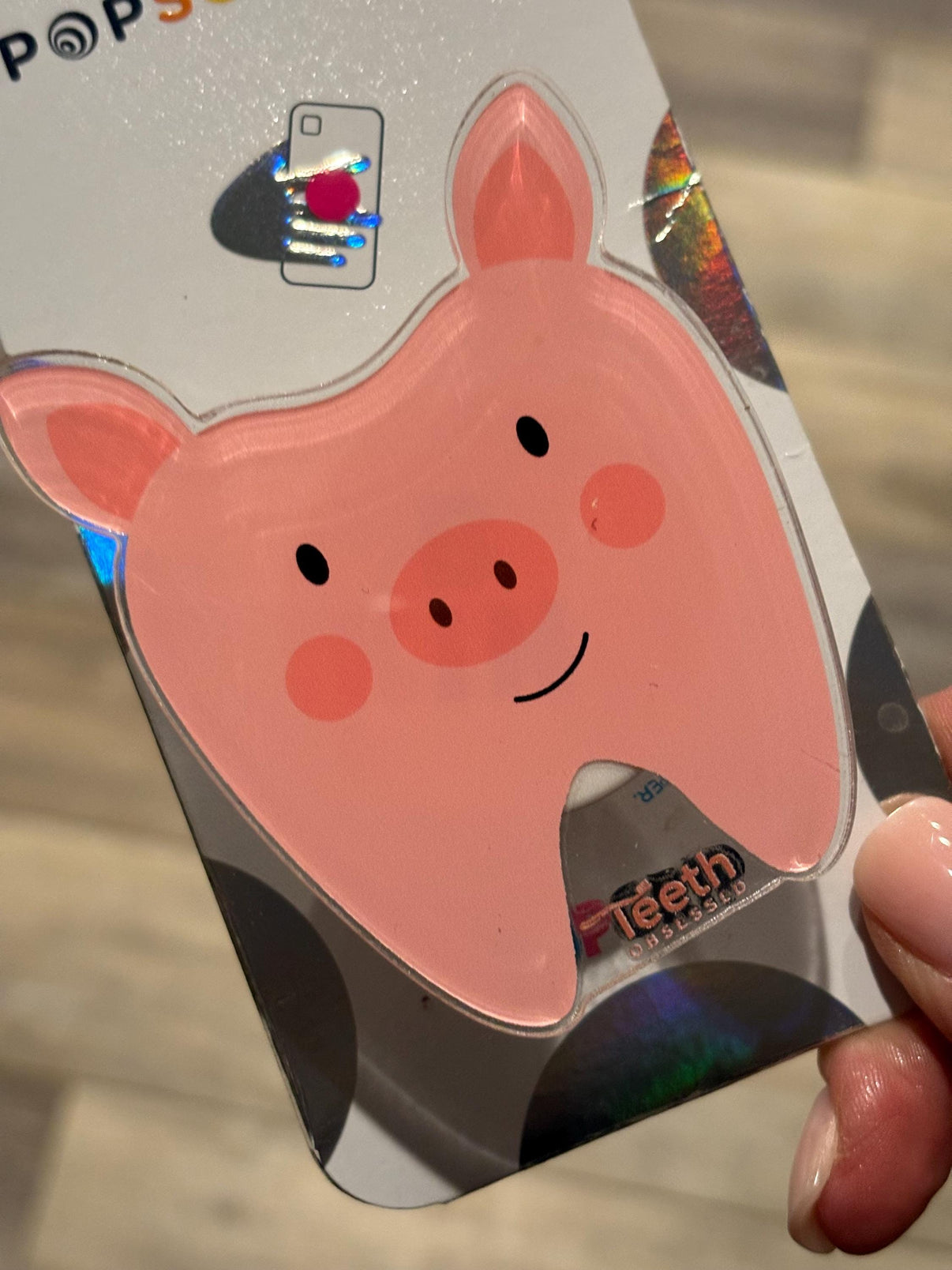 Teeth Obsessed pig tooth phone grip with a fun pig tooth design, used as a phone stand or grip for smartphones.